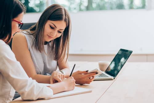 Two professionals discuss sales motivation tips during a meeting.